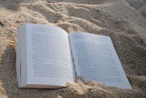 white book on sand during daytime